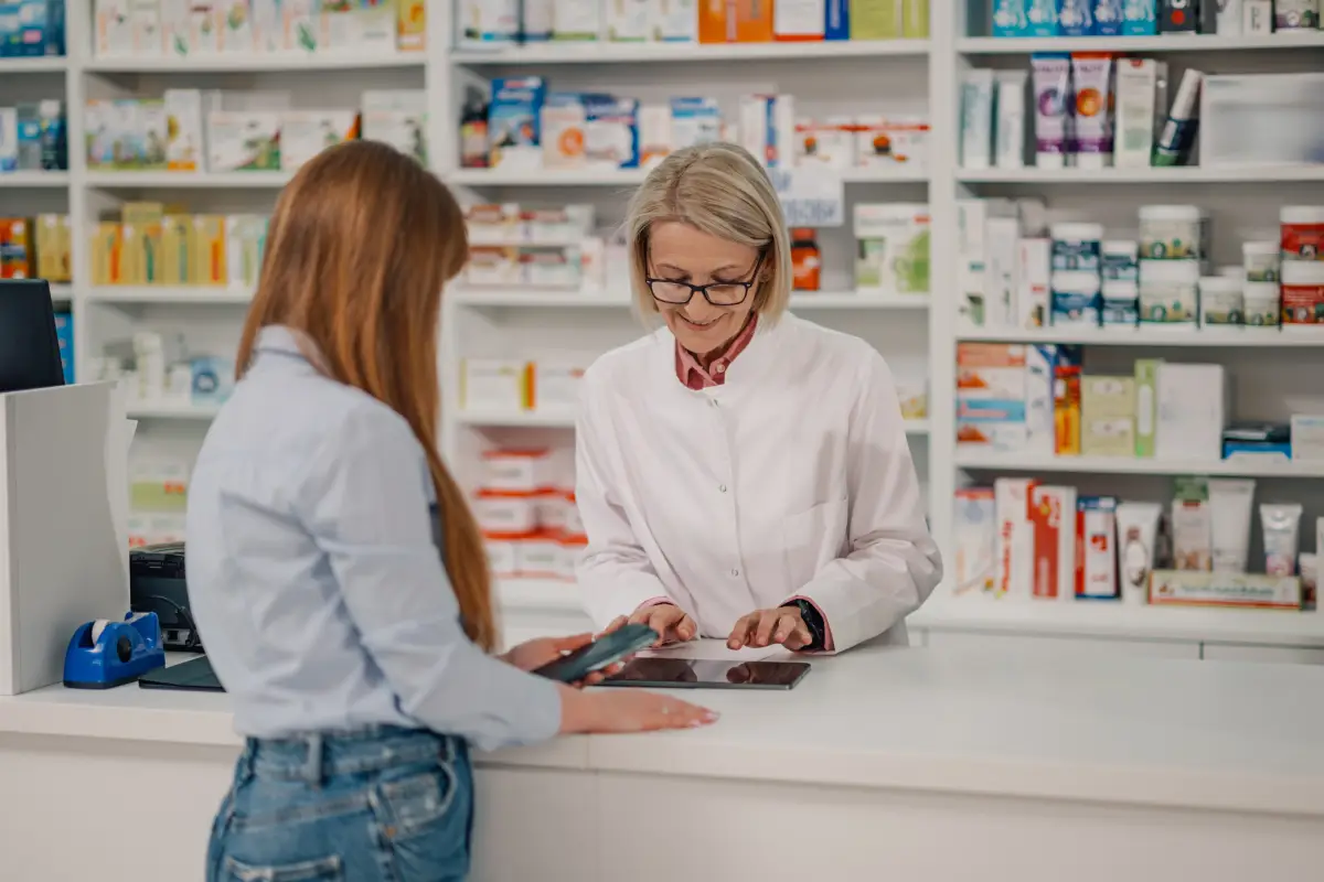 Farmaceutica-en-la-farmacia-usando-una-tableta-con-un-paciente